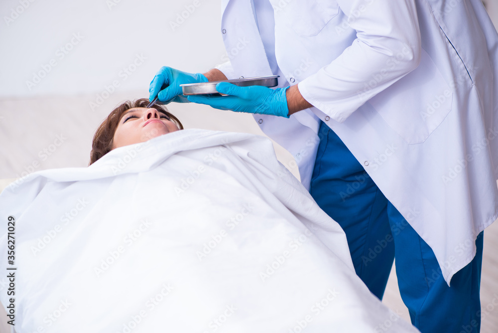 Police coroner examining dead body corpse in morgue Police coroner examining dead body corpse in morgue
