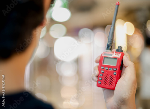 The male hand holding with a red Walkie Talkie or Portable radio transceiver for communication. photo