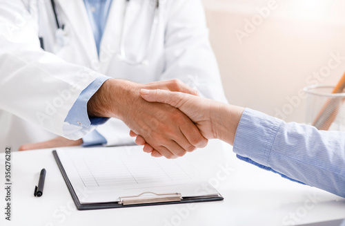 Senior female patient shaking hands with doctor