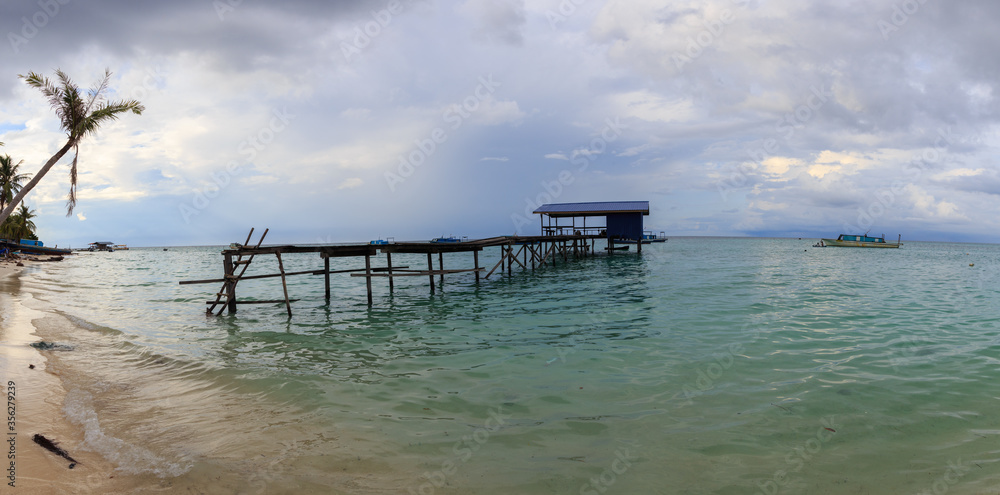 Beautiful scenery landscape view of long wooden jetty and white sand beach with blue sky ocean and green ocean