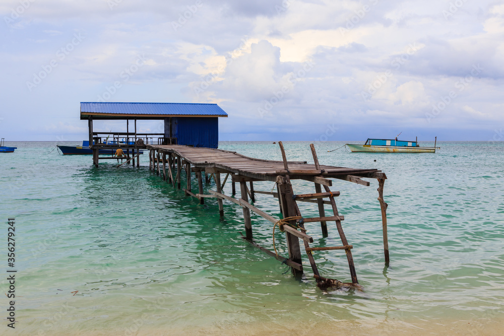 Beautiful scenery landscape view of long wooden jetty and white sand beach with blue sky ocean and green ocean