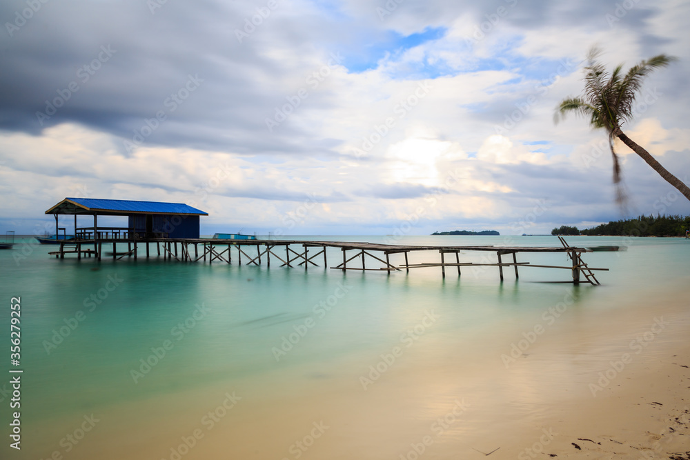 Beautiful scenery landscape view of long wooden jetty and white sand beach with blue sky ocean and green ocean