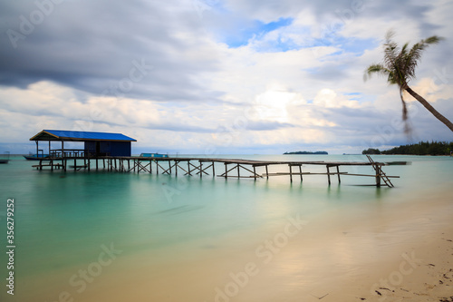 Beautiful scenery landscape view of long wooden jetty and white sand beach with blue sky ocean and green ocean © alenthien
