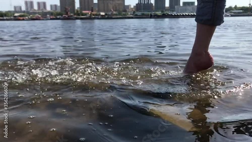 Spray with your foot. A man stands on a rocky bank of the river and makes a spray. Slow motion video