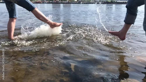 A guy and a girl are fooling around on the riverbank. They spray each other with water. Slow motion video.