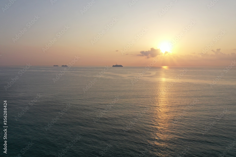 Aerial view of sunrise over ocean from Miami Beach, Florida with cruise ships at anchor on horizon.