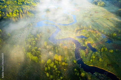 Natural landscape aerial view. Summer beautiful scenery in early morning. Brightly sunshine above misty river and meadow 