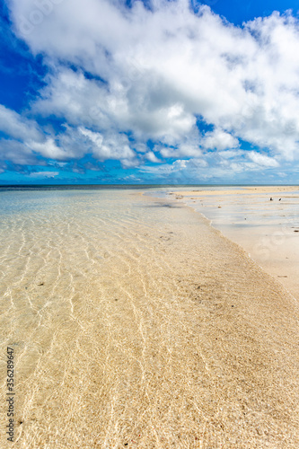 Water ripples on sandy beach with blue sky