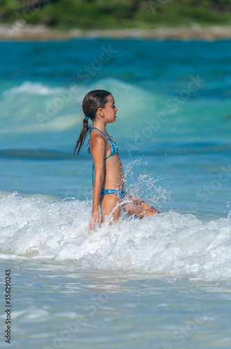 Niña con bikini azul entra chapoteando en aguas azules del Mar Caribe.  © Iván Gabaldón