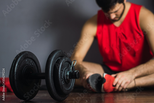 young man stretching after training with dumbbells