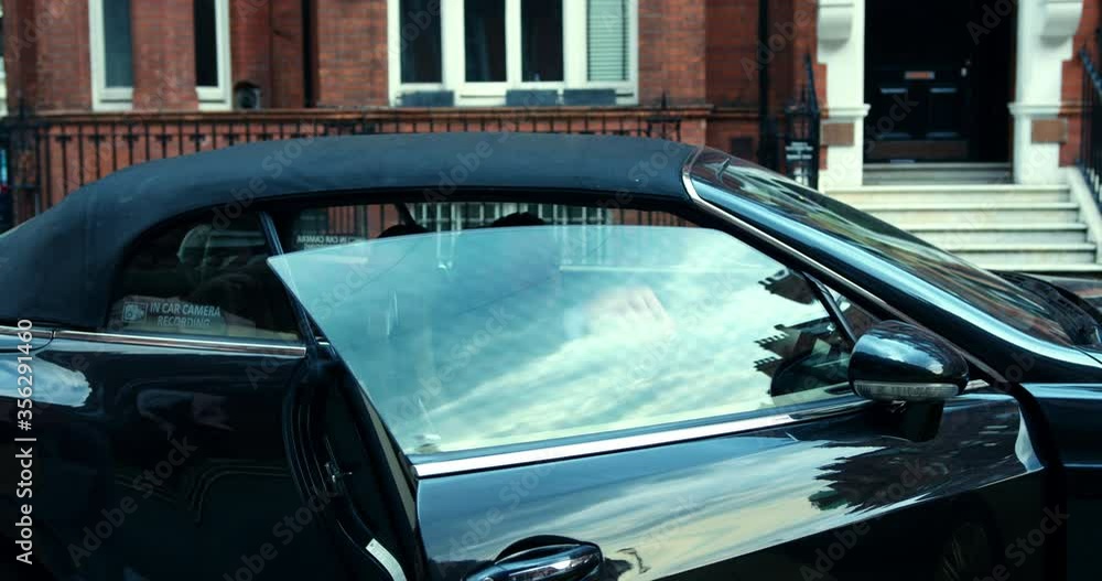 Bearded blond man getting into a black convertible in London, England.