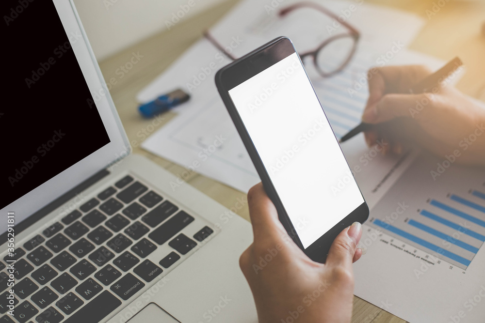 A woman holding and using mockup mobile phone with writing paper sheet on wooden table. A woman holding and using mockup mobile phone with writing paper sheet on wooden table.