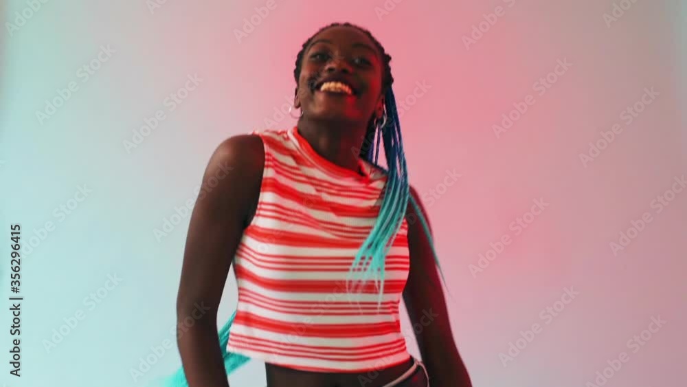 A young black girl with long turquoise plaits dancing to a rhythm, a strong beat. A young black girl with long turquoise plaits dancing to a rhythm, a strong beat.