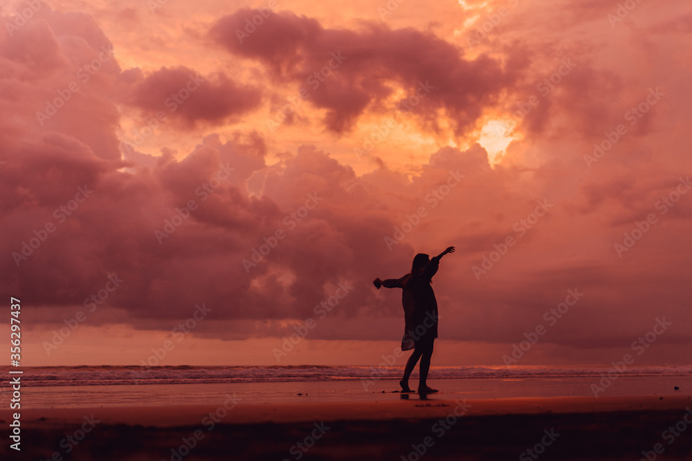 social distancing on the beach , pink and orange amazing cloudy sky , beautiful sunset , Bali Indonesia , solo outdoor walking 