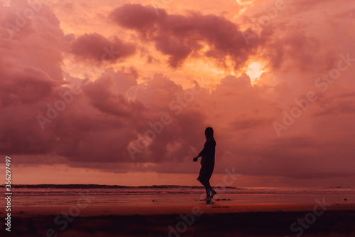 social distancing on the beach   pink and orange amazing cloudy sky   beautiful sunset   Bali Indonesia   solo outdoor walking 