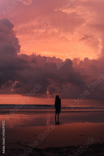 social distancing on the beach , pink and orange amazing cloudy sky , beautiful sunset , Bali Indonesia , solo outdoor walking 