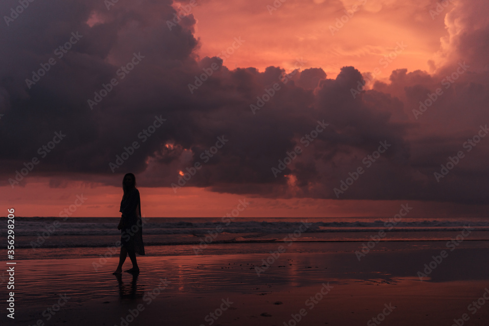 social distancing on the beach , pink and orange amazing cloudy sky , beautiful sunset , Bali Indonesia , solo outdoor walking 