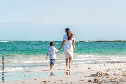 Mujer y niño con ropa de verano pasea juntos en playa del mar Caribe durante las vacaciones.