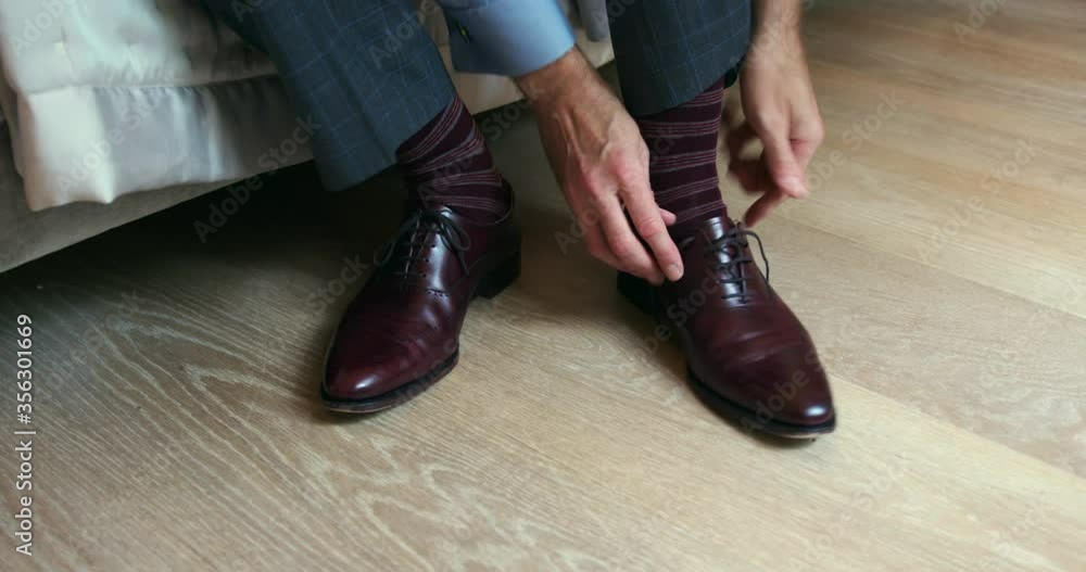 Close up of man tying laces of his brown leather shoes. Close up of man tying laces of his brown leather shoes.