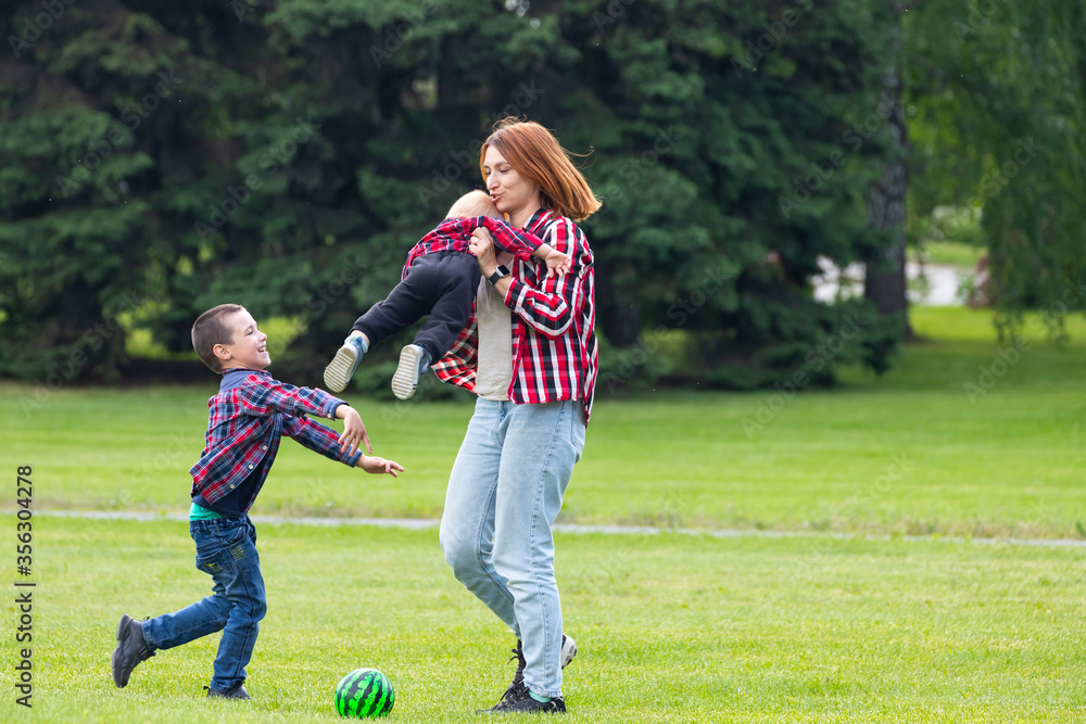 Happy young mother is playing with ball with her baby in a park on a green lawn.Concept of a happy family. Mothers Day. Happy young mother is playing with ball with her baby in a park on a green lawn.Concept of a happy family. Mothers Day.