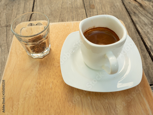 Fototapeta Naklejka Na Ścianę i Meble -  Espresso coffee in a white cup with  a glass of brown sugar, Hot drink with brown table in background