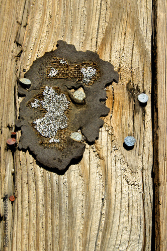 Remnant tar paper with nails on sandblasted wall photo