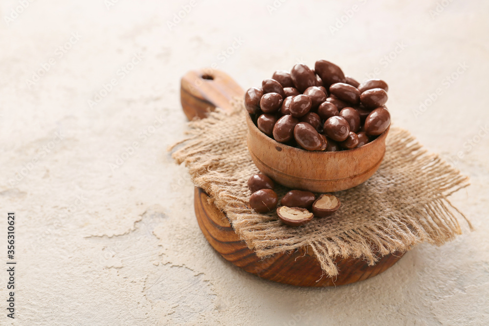 Bowl with tasty chocolate nuts on white background