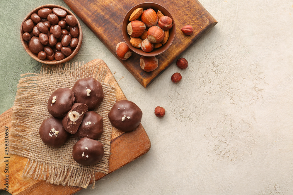 Tasty chocolate candies with nuts on light background