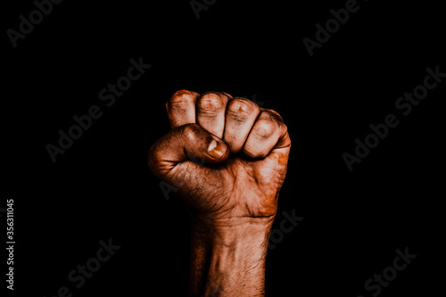 Male black fist on a black background. Aggressiveness, masculinity, the concept of challenge photo