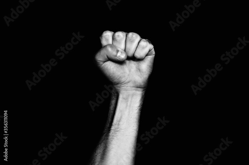 Male black fist on a black background. Aggressiveness, masculinity, the concept of challenge photo