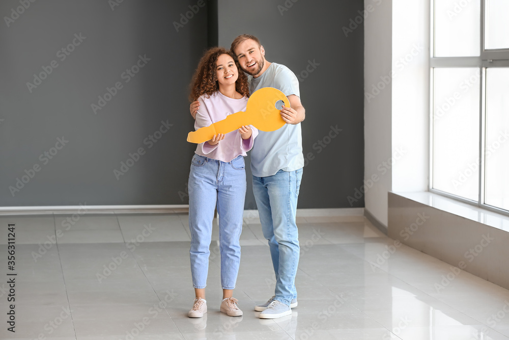 Happy young couple with big paper key in their new flat Happy young couple with big paper key in their new flat