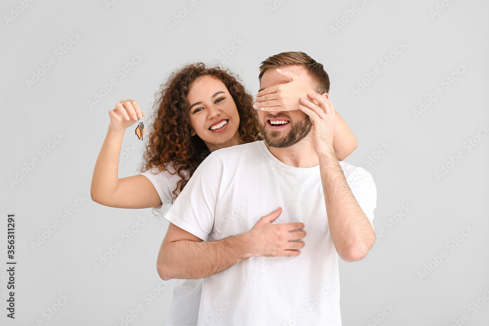 Happy young couple with key on grey background Happy young couple with key on grey background