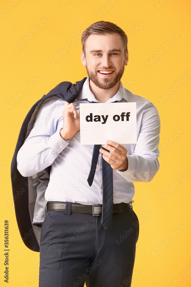 Young businessman holding paper with text DAY OFF against color background Young businessman holding paper with text DAY OFF against color background
