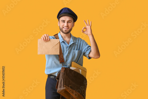 Handsome young postman on color background photo