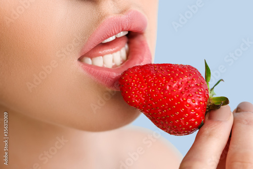 Sexy young woman with strawberry on color background  closeup