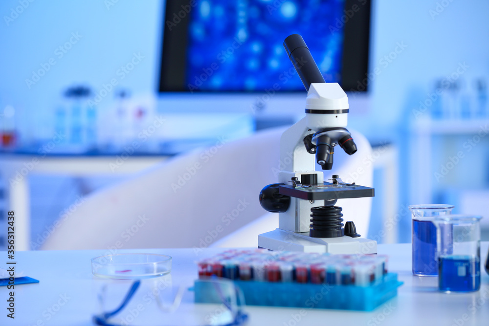 Microscope and glassware on table in laboratory Microscope and glassware on table in laboratory