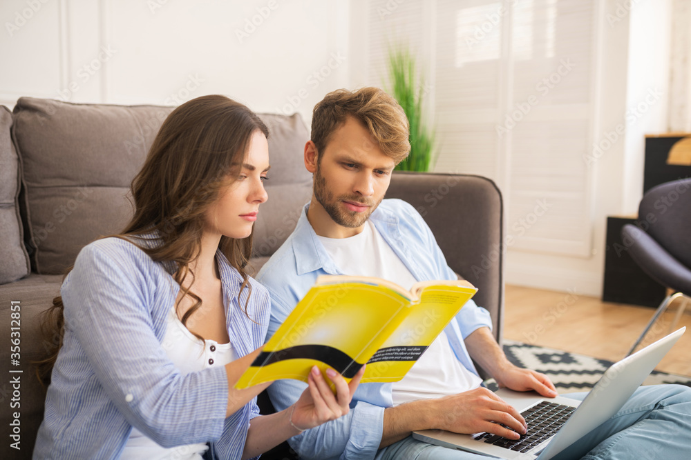 Young couple looking interested, woman showing something in a book Young couple looking interested, woman showing something in a book