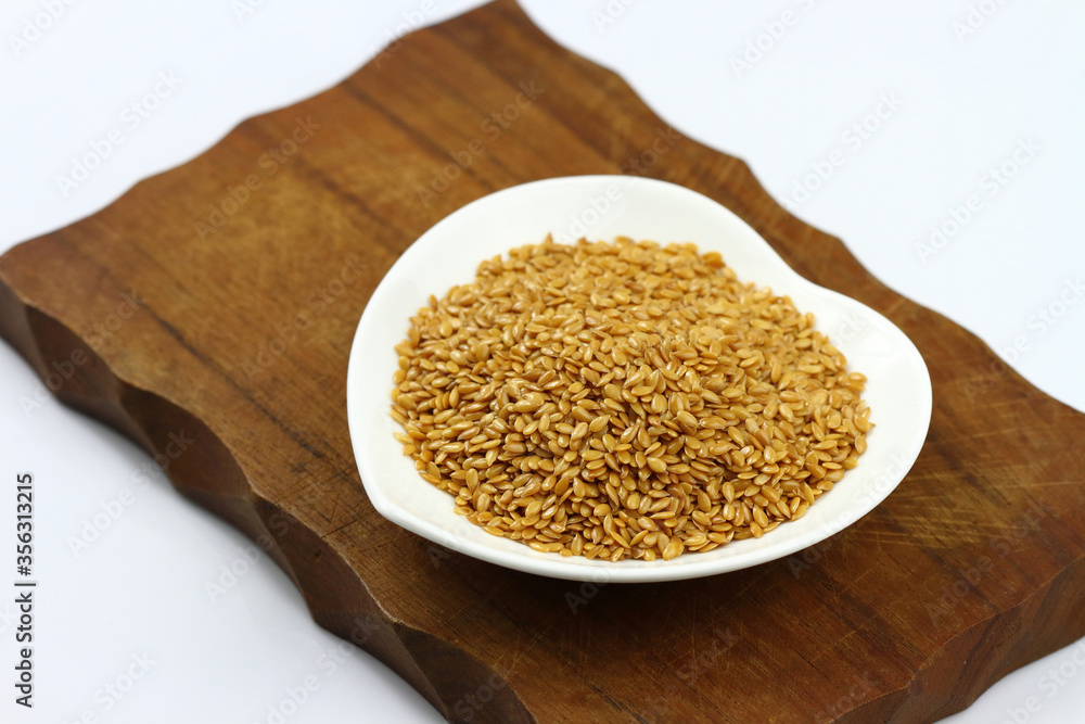 Flax seeds in a white ceramic bowl shape heart on wooden board Flax seeds in a white ceramic bowl shape heart on wooden board