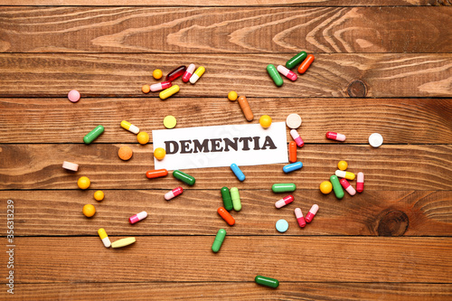 Word DEMENTIA with pills on wooden background