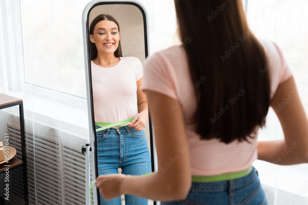 Excited Girl Measuring Thin Waist Looking In Mirror At Home