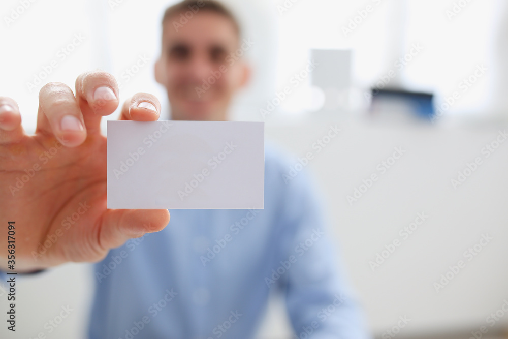 Smiling business man in suit hold in hand blank calling card closeup. White collar partners company name exchange executive or ceo introducing at conference product consultant sales clerk concept Smiling business man in suit hold in hand blank calling card closeup. White collar partners company name exchange executive or ceo introducing at conference product consultant sales clerk concept