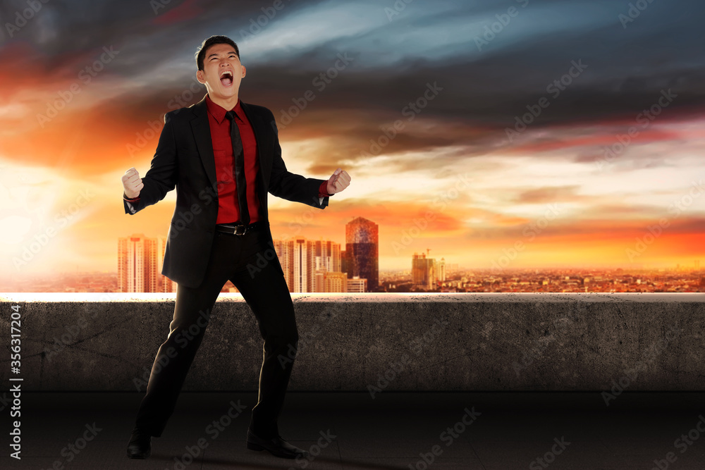 Fototapeta premium Asian businessman celebrating his successful standing on office terrace
