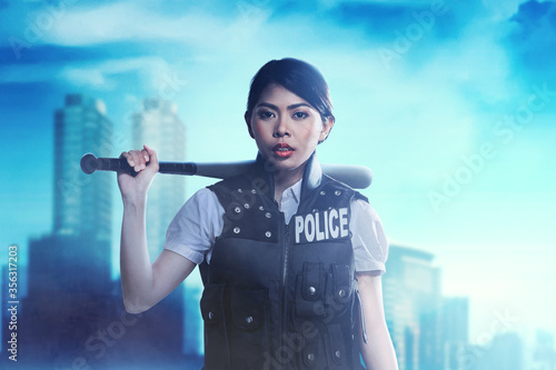 Εκτύπωση καμβά Asian woman in police vest standing with a baseball bat