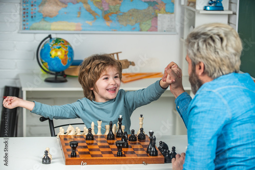 Young kid boy playing chess with father and having fun. Education and learning people concept - pupil and Teacher. photo