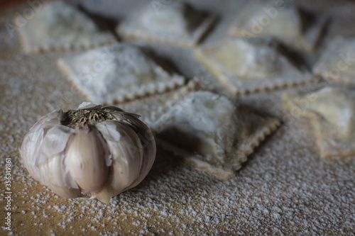 homemade garlic ravioli on wood and loose flour