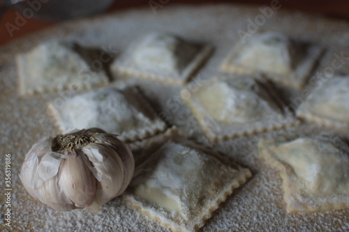 homemade garlic ravioli on wood and loose flour