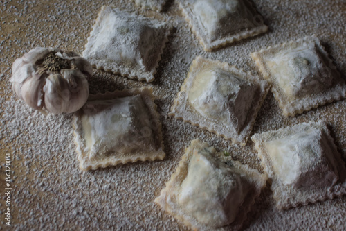 homemade garlic ravioli on wood and loose flour