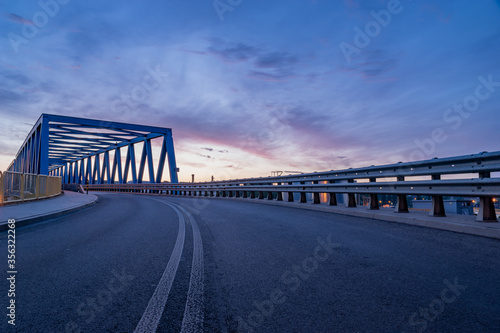asphalt road and truss steel bridge during dusk