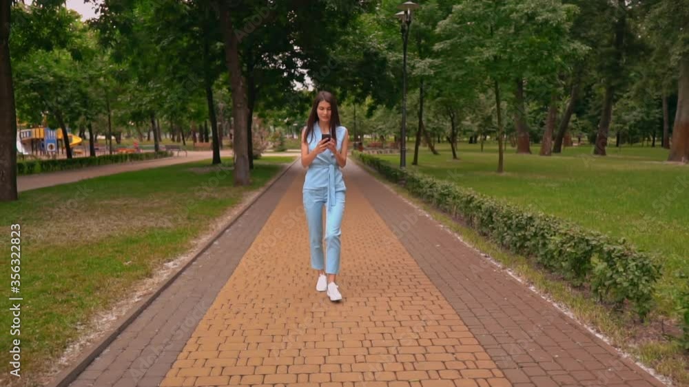 young woman in blue suit holding smartphone raising hand celebrating success walking on the street slow motion young woman in blue suit holding smartphone raising hand celebrating success walking on the street slow motion