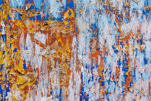 Minimalist colourful textured background of old and rusted whit, blue, brown and orange paing on metallic surface, in direct sun light in an urban environment.